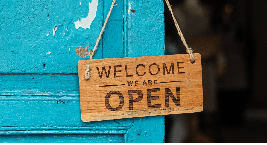 A wooden welcome sign on a azure blue restaurant door