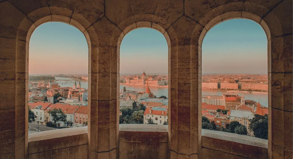 The skyline of Budapest seen through three window arches without glass