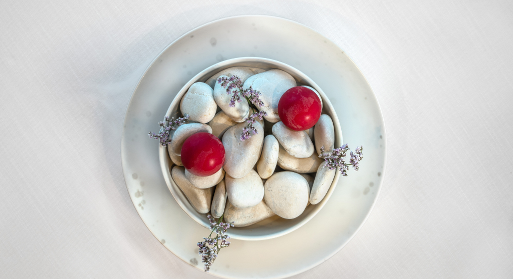 A dish from restaurant Palace in Helsinki. The food is served in a bowl of white pebbles decorated with violet flowers.
