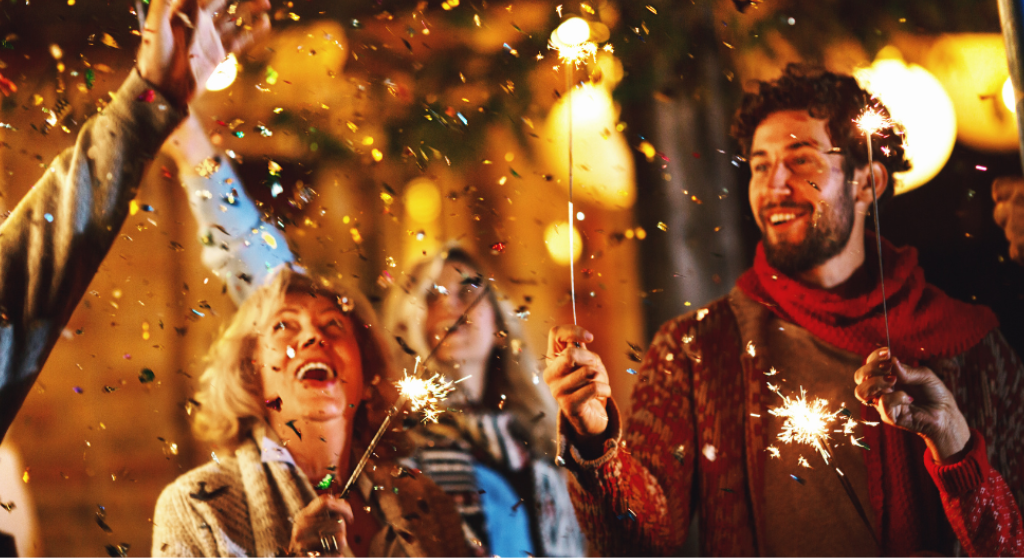 Smiling people with sparklers and confetti at a New Year's event. 