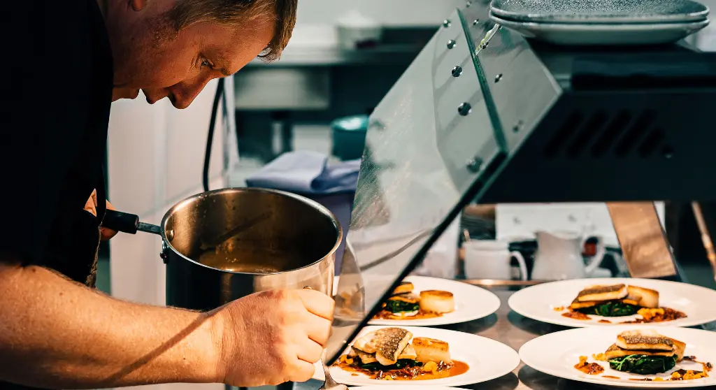A chef plating dishes in a restaurant kitchen