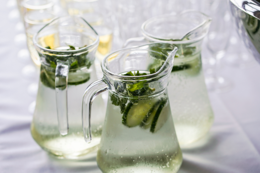 Three full water jugs with cucumb slices and mint. 